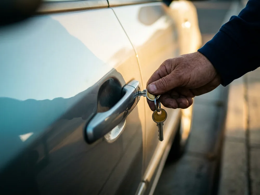 Key turning cleanly in a car door lock after the repair, shot along the door flank