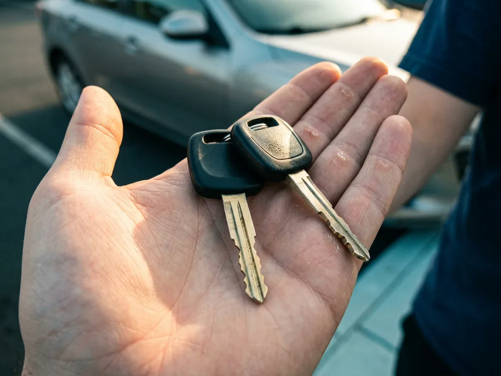 Two freshly cut car keys lying across an open palm at the customer vehicle